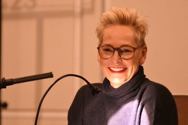 Eine Frau mit Brille spricht in ein Mikrofon.